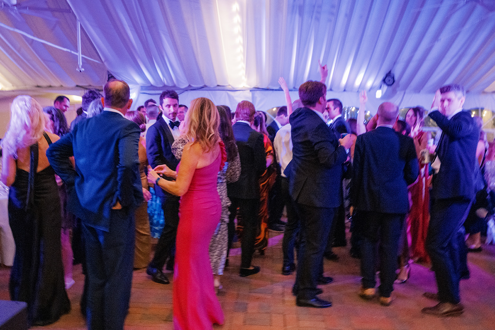 Wedding guests on a dance floor under purple and blue event lighting at the Taft Museum