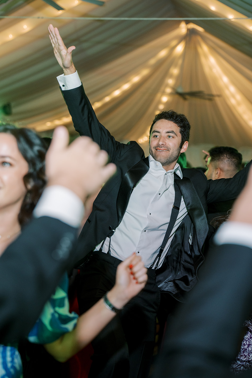 Wedding guest celebrating beneath a warmly illuminated tent ceiling at the Taft Museum