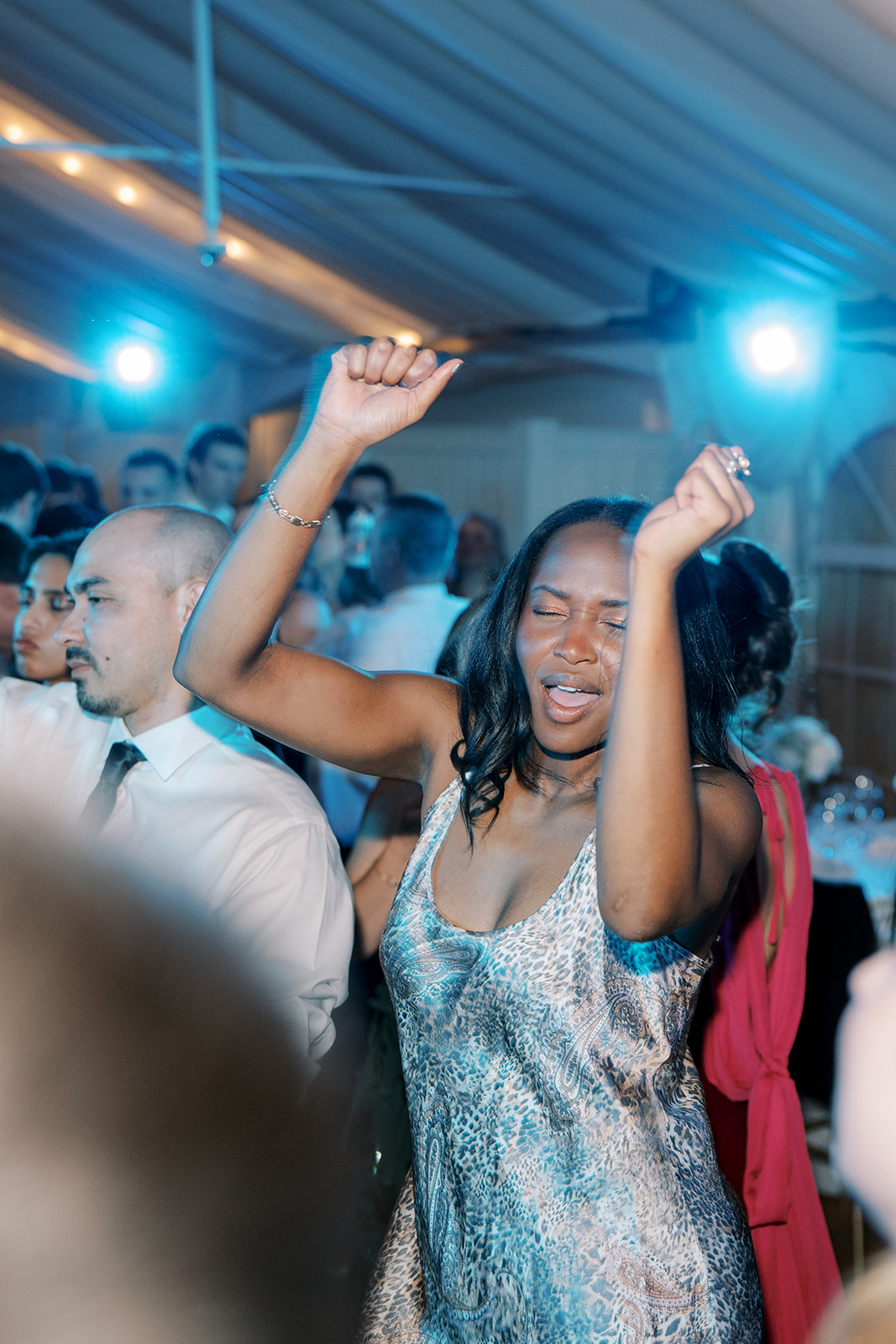 Wedding guest dancing beneath bright blue dance-floor lights at the Taft Museum