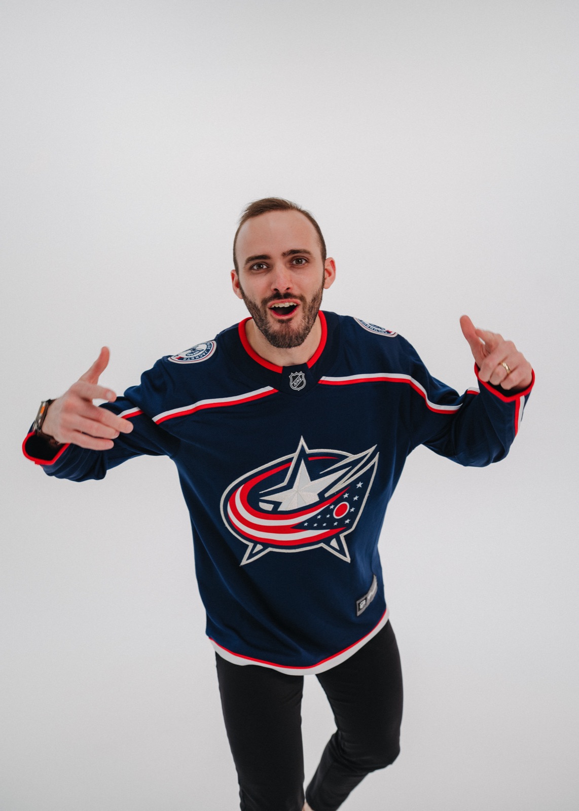Vince K wearing a Columbus Blue Jackets jersey in a playful studio portrait