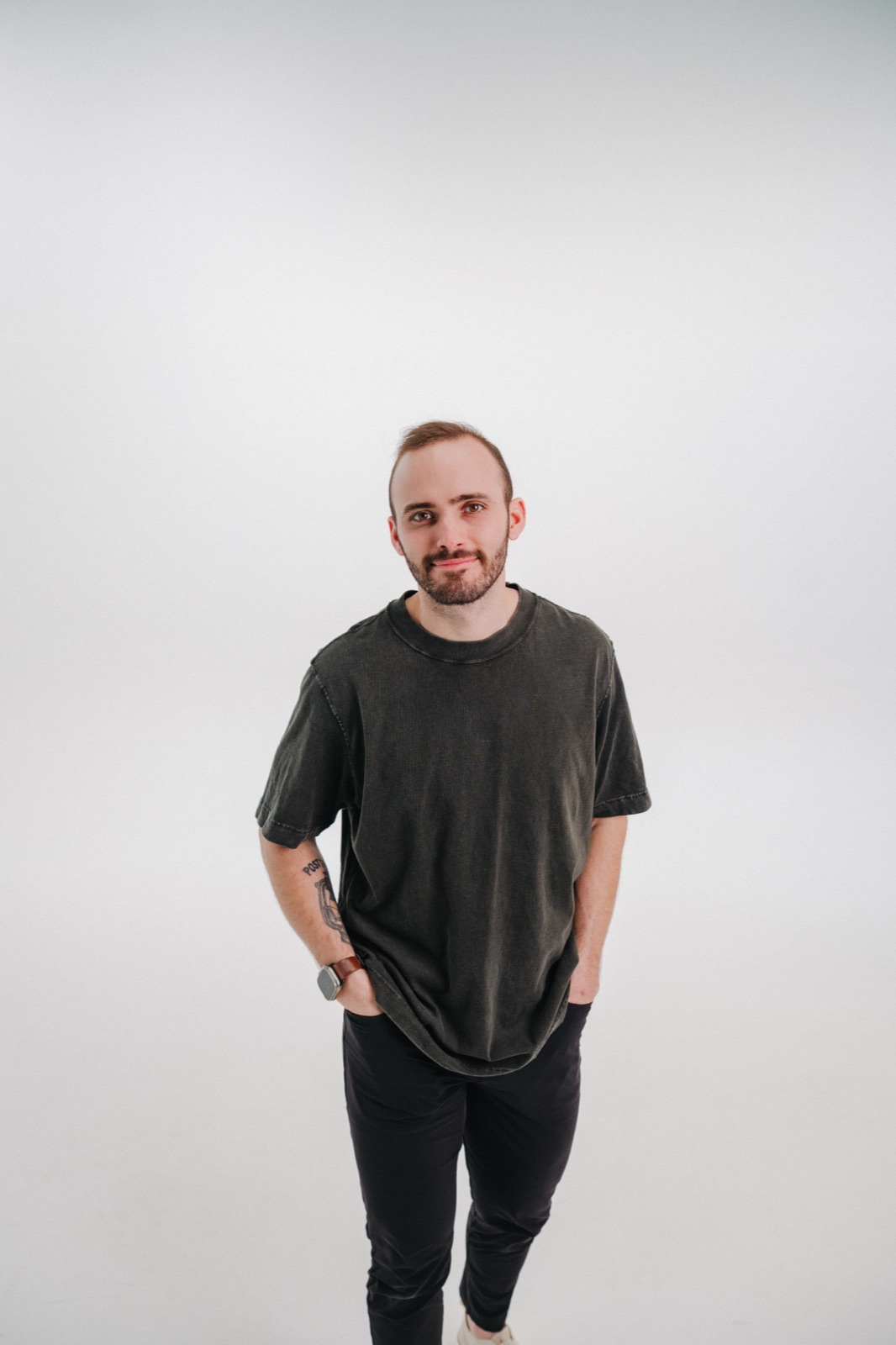 Vince K in a dark T-shirt, hands in pockets, against a light studio backdrop