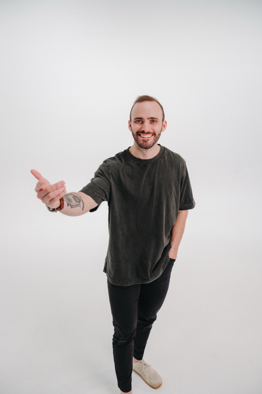 Vince K smiling and reaching toward the camera in a casual studio portrait